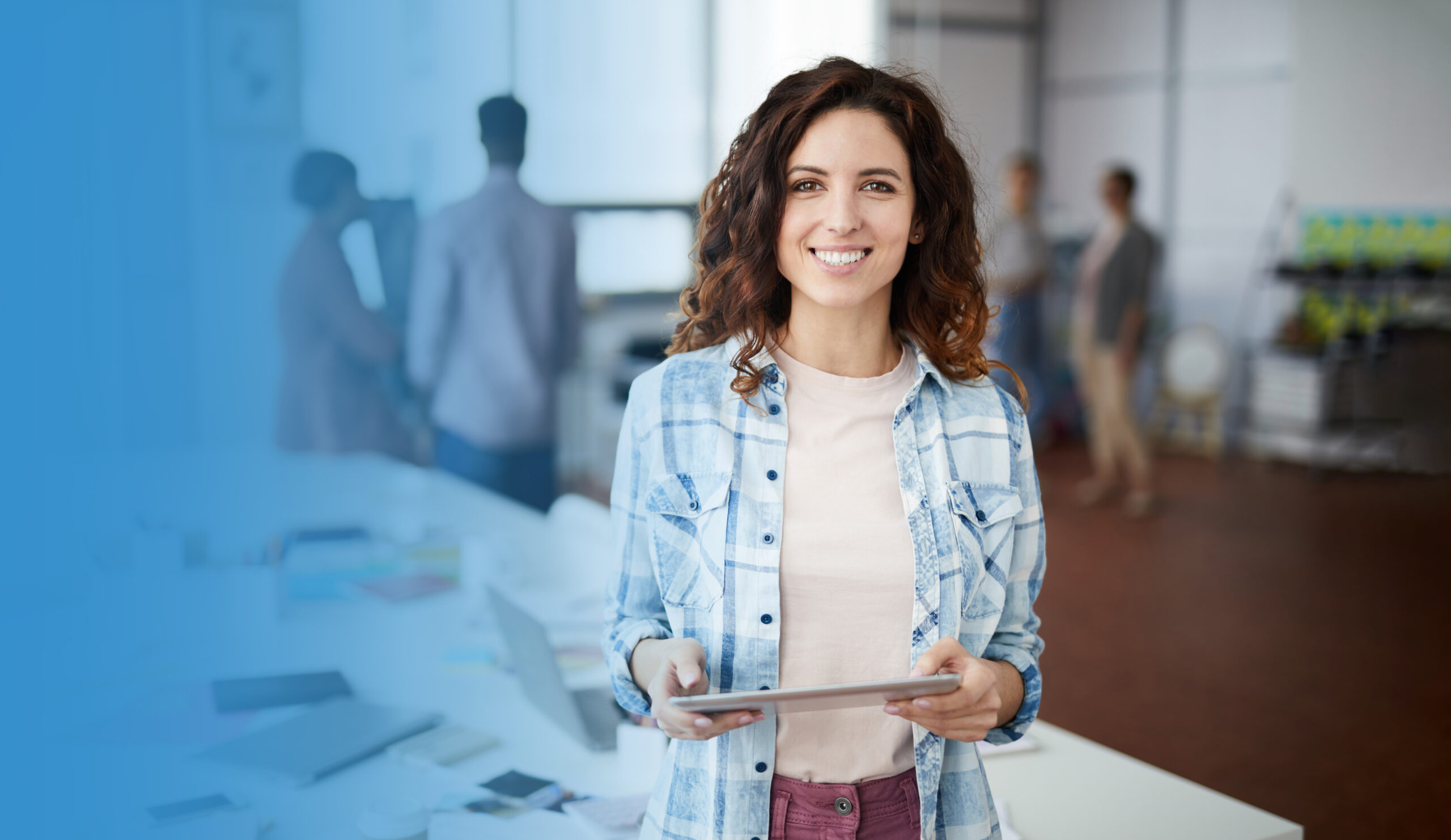 Waist up portrait of creative young woman smiling at camera and holding digital tablet while standing in modern office, copy space